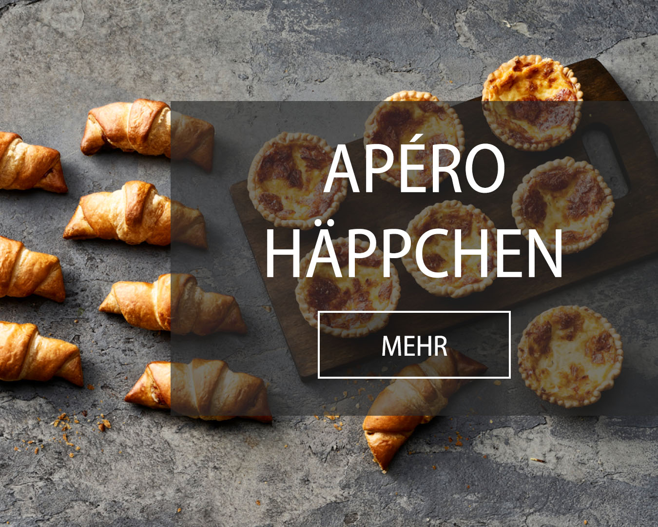 Apéro Häppchen wie Schinkengipfeli und Chäschüechli werden auf Holzbrett präsentiert.